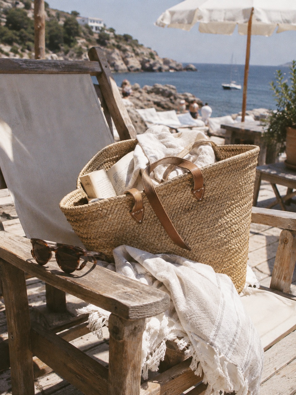 Straw tote with a silk scarf on a seaside café table