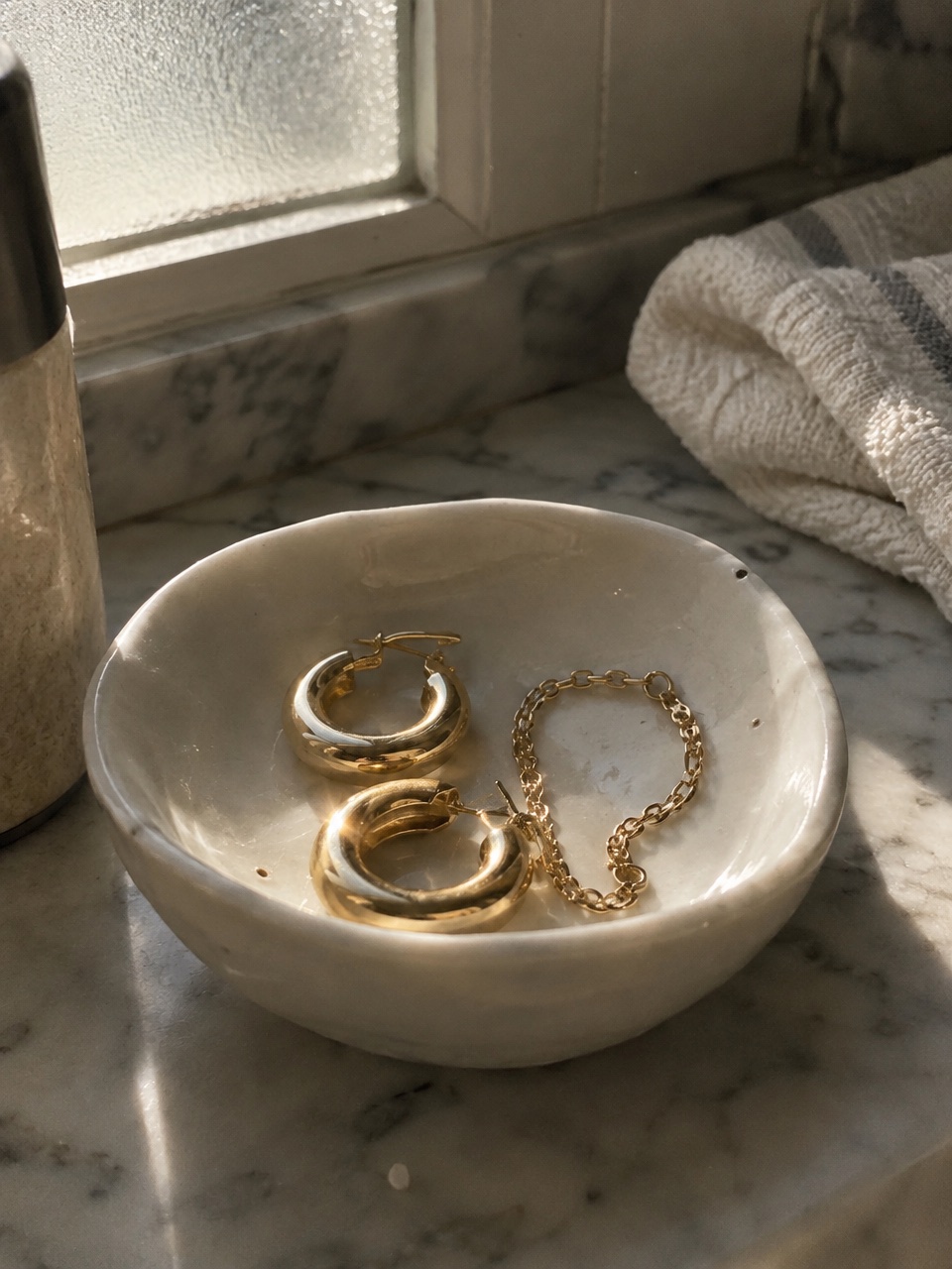Gold hoop earrings in a porcelain dish